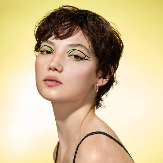 A light skin model, wearing Stretch The Limits Liner, liquid eyeliner in Lime and Black.